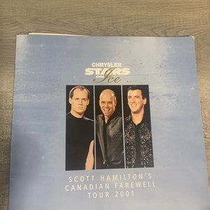 Könnte beinhalten: Ein blaues und weißes Programm für Scott Hamiltons kanadische Abschiedstournee 2001. Das Programm zeigt ein Foto von drei Männern, das Chrysler Stars on Ice Logo und den Text "Scott Hamilton's Canadian Farewell Tour 2001".