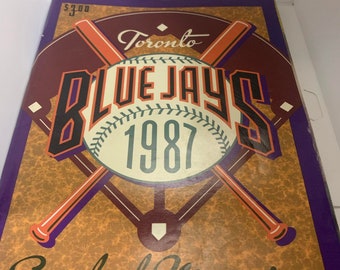 May include: A vintage Toronto Blue Jays 1987 Scorebook Magazine with a baseball and crossed bats design. The cover is brown, orange, and white with a purple border.