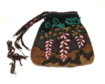 May include: A beaded handbag with a floral design. The bag features a dark background with brown, green, and white floral accents. The handle and tassel are dark brown. The bag is likely vintage or antique.