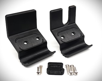 May include: Two black plastic wall mounts with two screw holes each, designed to hold a cylindrical object. The mounts have a curved lip on the bottom.  A small black plastic piece and four silver screws are also included.