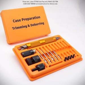 May include: An orange case labelled "Case Preparation Trimming & Deburring" holds various tools. The kit includes a gold-coloured trimmer, several black components, and silver rods. The case is open, displaying the tools.