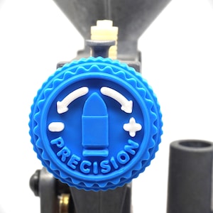 Op de afbeelding: Een blauwe knop met witte pijlen en een kogelafbeelding. De knop is gelabeld "PRECISION".