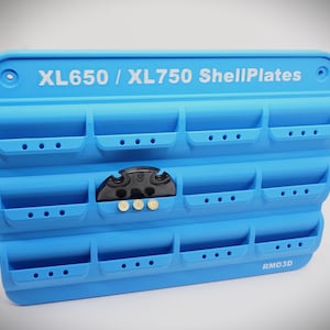 May include: A light blue XL650 / XL750 ShellPlates organizer with multiple compartments. The organizer has the text "XL650 / XL750 ShellPlates" and "RMD3D" printed on it. A black object and three small white objects are placed in the organizer.
