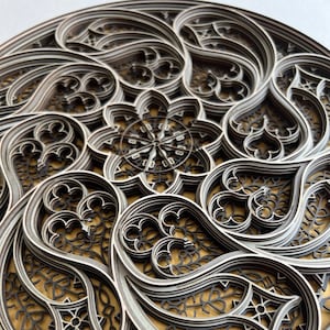 May include: A circular, layered, wooden wall art piece with an intricate, geometric design in shades of grey and brown.