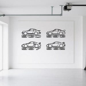 May include: Four black metal car silhouettes mounted on a white wall. Each silhouette features a different car model with the model number below. The cars are in a garage setting.