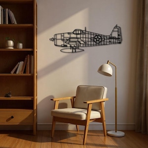 May include: A black metal wall art piece depicting a vintage airplane silhouette. The artwork features intricate cut-out details, including the wings, fuselage, and tail. A star is visible on the side of the plane. The art is mounted on a neutral-colored wall.