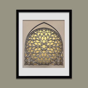 Può includere: Una stampa incorniciata di una finestra decorativa dorata e argentata con un design circolare. La finestra è incorniciata in nero e ha uno sfondo beige.