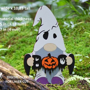 May include: A white ghost gnome holding a black "BOO" sign and a carved orange pumpkin with a dripping face. The gnome is 6.73 inches wide and 10.23 inches tall. Digital files for laser cutting.