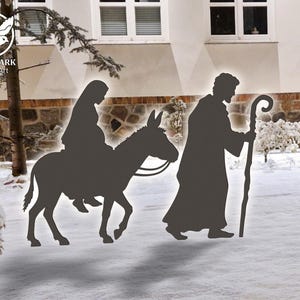 May include: A dark silhouette of a religious scene. A person rides a donkey, followed by another person carrying a staff. The background shows a snowy landscape with a building and trees. The image is a vector art design.