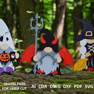 May include: Three Halloween gnomes, one dressed as a ghost holding a pumpkin and a sign that says "Boo", one dressed as a devil with red wings and a trident, and one dressed as a witch with a black hat and a broom.