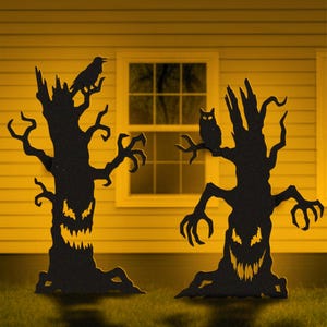 May include: Two black silhouette tree cutouts with jagged, glowing yellow eyes and mouths. One tree features a perched crow, the other an owl. Text reads: PDF File: US Letter / A4 Prints, AI, CDR, DWG, DXF, SVG: CNC / Laser Cutting, LUCKY LARK Vector Art.