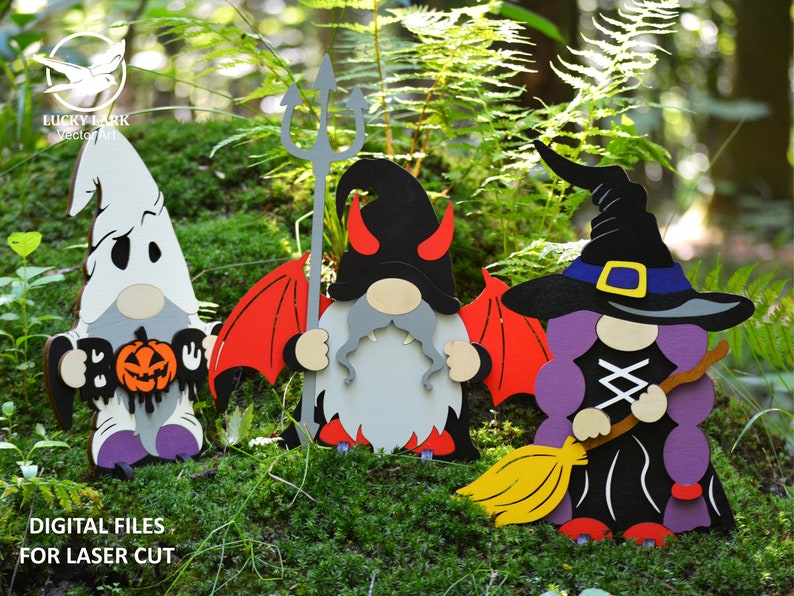 May include: Three Halloween gnomes, one dressed as a ghost holding a jack-o-lantern, one dressed as a devil with red wings and a trident, and one dressed as a witch with a purple hat and a broom.