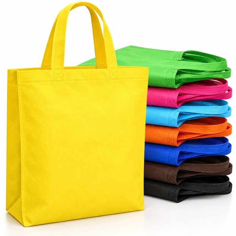 May include: A collection of rectangular tote bags made of non-woven fabric, featuring a vertical orientation with two top handles. The bags are stacked in a vibrant array of colors including yellow, lime green, pink, light blue, orange, blue, brown, and black.