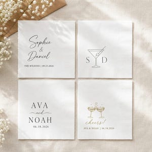 May include: Four square white paper napkins featuring custom black and gold printed designs. The napkins display names like Sophie & Daniel and Ava and Noah, along with dates, martini glass graphics, and the text cheers with a small heart icon.
