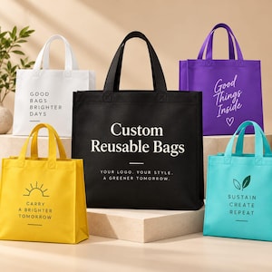 May include: A collection of five reusable tote bags in white, black, yellow, purple, and turquoise. Each bag features unique printed text and graphics, including phrases like Good Bags Brighter Days, Custom Reusable Bags, and Sustain Create Repeat.