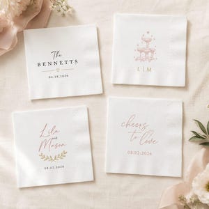 May include: Four square white paper napkins featuring custom printed designs. One displays The Bennetts with 18.04.2026, another a fountain with L|M, one shows Lila and Mason with 02.08.2026 and a leaf motif, and the last reads cheers to love with 02.08.2026.