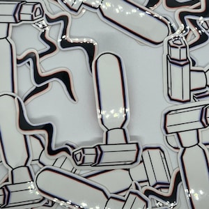 May include: A collection of white stickers featuring a black and white line drawing of a security camera. The stickers have a glossy finish and are accented with red and blue lines. The background is white.