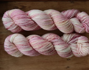 May include: Two skeins of pink, white, and cream yarn with a speckled effect.