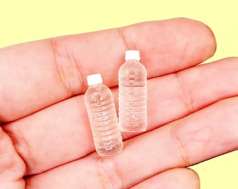 May include: Two miniature plastic water bottles with white caps. The bottles are clear and have a textured surface.