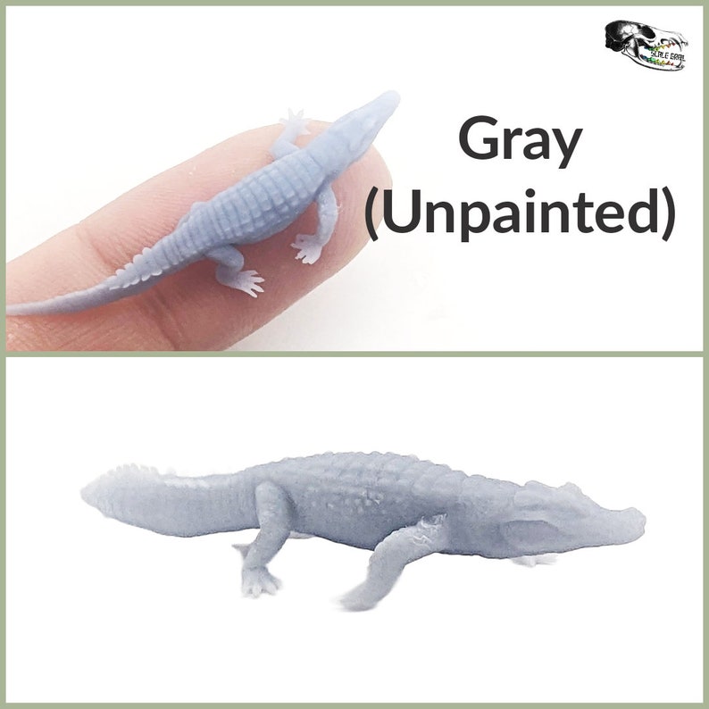 May include: Gray unpainted alligator figurine. The alligator is posed with its mouth closed and its legs outstretched. The figurine is made of a smooth, gray plastic.