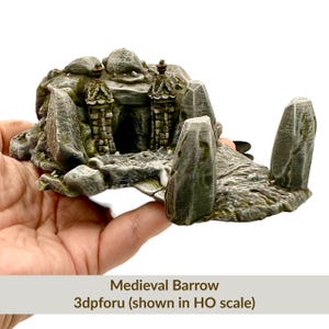 May include: A miniature medieval barrow model, featuring a stone structure with two tower-like structures flanking a central entrance. The model is gray and green, with a textured surface. The text "Medieval Barrow" and "3dpforu (shown in HO scale)" is visible.