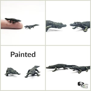 May include: Four miniature painted alligator figurines. The alligators are green and brown with textured details. The word "Painted" is written in black text on a white background.