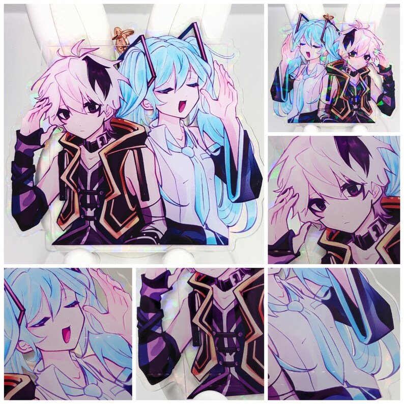 Pode incluir: Um pingente de acr&iacute;lico transparente com dois personagens em estilo anime e detalhes hologr&aacute;ficos. Um personagem tem cabelo azul claro e camisa branca, enquanto o outro tem cabelo branco com mechas pretas e um colete preto e dourado em acr&iacute;lico.