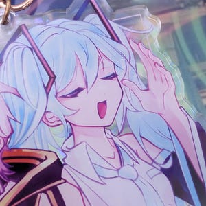 Pode incluir: Um porta-chaves de acr&iacute;lico transparente com um personagem de estilo anime impresso com cabelo azul claro em duas tran&ccedil;as, vestindo uma camisa branca de colarinho com gravata. O personagem tem os olhos fechados e a boca aberta, preso a um anel de metal ouro rosa.