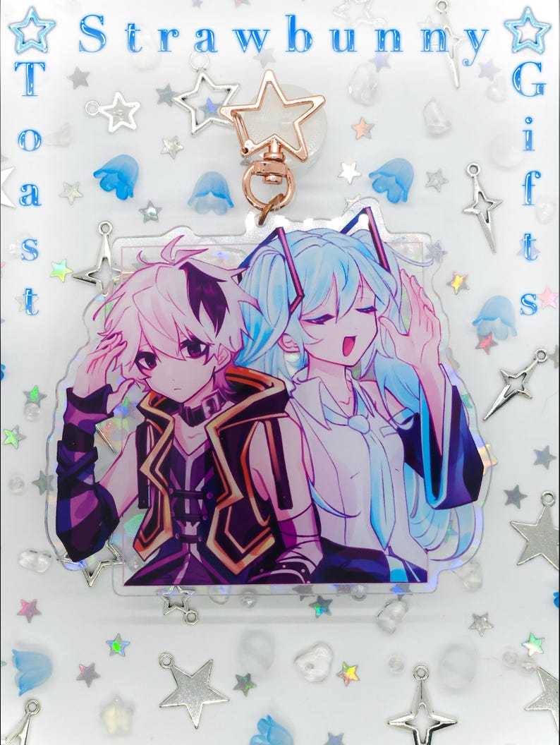 Pode incluir: Um chaveiro de acr&iacute;lico com uma ilustra&ccedil;&atilde;o estilo anime de dois personagens, um com cabelo curto rosa e colete escuro, o outro com cabelo longo azul claro. O chaveiro tem um fecho em forma de estrela e o texto Strawbunny Toast Gifts.
