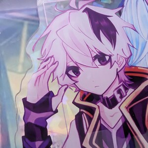 Pode incluir: Um pingente de acr&iacute;lico com um personagem estilo anime de cabelo lavanda claro, olhos roxos escuros e uma roupa preta e roxa. O personagem tem uma m&atilde;o perto da cabe&ccedil;a e &eacute; feito de um material transparente e brilhante com um aro met&aacute;lico.