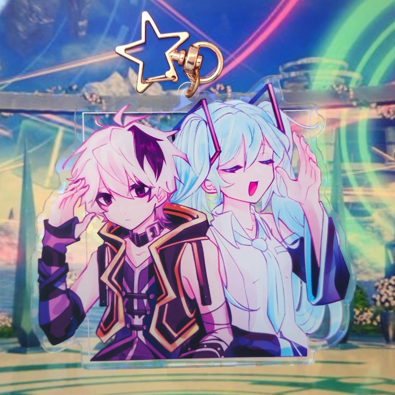 Pode incluir: Um porta-chaves de acr&iacute;lico transparente com um fecho em forma de estrela e uma ilustra&ccedil;&atilde;o impressa de duas personagens de estilo anime. Uma personagem tem cabelo branco curto com detalhes escuros e a outra tem cabelo comprido azul-claro.