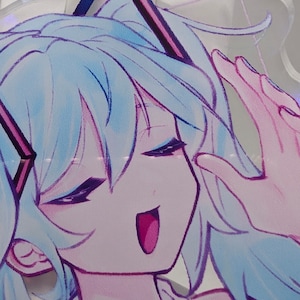 Pode incluir: Um expositor de acr&iacute;lico transparente com uma ilustra&ccedil;&atilde;o impressa de uma personagem com cabelo azul claro, olhos fechados e boca aberta. A personagem tem contornos roxos escuros e usa um acess&oacute;rio de cabelo triangular roxo escuro.