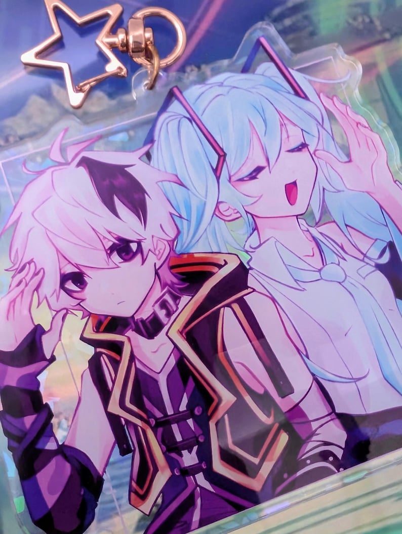 Pode incluir: Um porta-chaves de acr&iacute;lico transparente com uma ilustra&ccedil;&atilde;o impressa de duas personagens de estilo anime. Uma personagem tem cabelo branco curto e um traje preto e roxo, enquanto a outra tem cabelo comprido azul claro. Inclui um fecho em forma de estrela em ouro rosa.