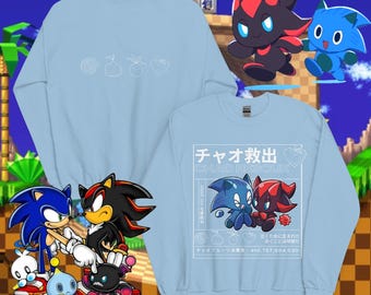 May include: Two light blue sweatshirts. One has white line drawings of a spiral, a pear, a strawberry, and a heart. The other has Japanese text and cartoon characters. The background is a video game scene with Sonic the Hedgehog characters.