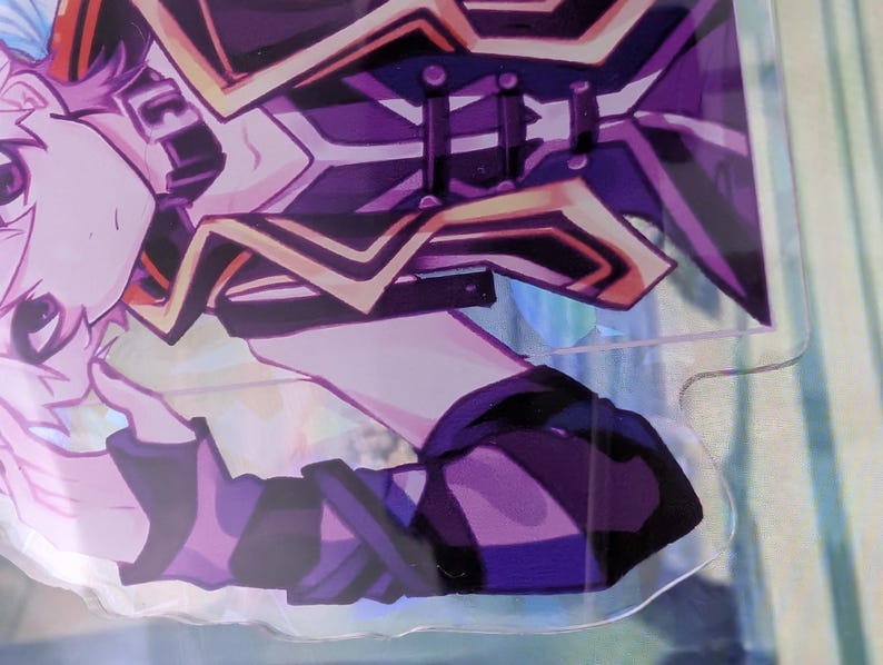 Pode incluir: Um expositor de acr&iacute;lico transparente com uma personagem de estilo anime de cabelo rosa claro, vestindo um traje roxo escuro e preto com detalhes dourados. A personagem &eacute; representada do peito para cima, com uma m&atilde;o perto do queixo.