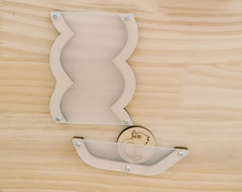 May include: A wooden toy with a clear plastic track and a wooden bird shape. The track is shaped like a wavy line and the bird shape is placed at the bottom of the track. The toy is mounted on a light brown wooden surface. The text "IK DreamToy" is visible in the top left corner of the image.