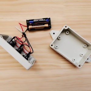 May include: Two white plastic project boxes with a battery pack and wires. The battery pack is labeled "VIRKLAND".