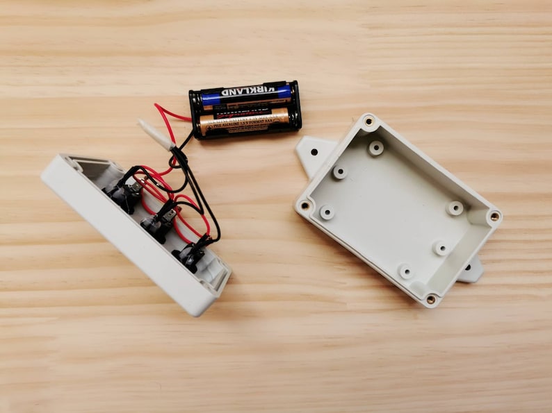 May include: Two white plastic project boxes with a battery pack and wires. The battery pack is labeled "VIRKLAND".