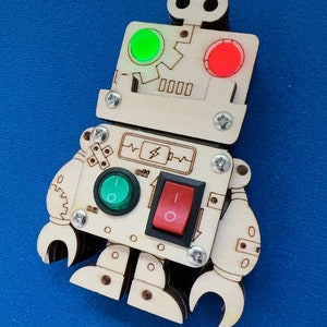 May include: A wooden robot toy with a green and red light, a toggle switch, and the word "off" printed on it.