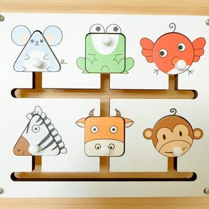 May include: A wooden animal puzzle with a mouse, frog, bird, zebra, cow, and monkey. Each animal is a different shape and colour, with a white knob for easy handling. The puzzle is mounted on a light wood base.