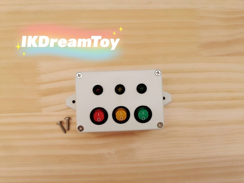 A white plastic box with three red, yellow, and green toggle switches and three corresponding indicator lights for Traffic Light Switch Busy Board Part