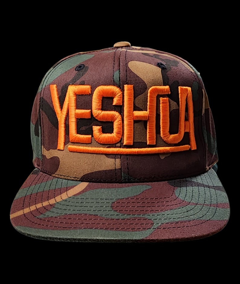 May include: A camouflage baseball cap with the word "YESHUA" embroidered in orange on the front.