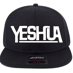 May include: Black and white snap back baseball cap with the word "YESHUA" in white letters on the front.