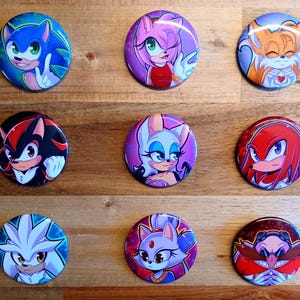 Op de afbeelding: Negen kleurrijke ronde buttons met personages uit de Sonic the Hedgehog-videogameserie. De buttons tonen personages als Sonic, Amy Rose, Tails, Shadow, Rouge, Knuckles, Silver, Blaze en Dr. Eggman, elk met unieke ontwerpen.