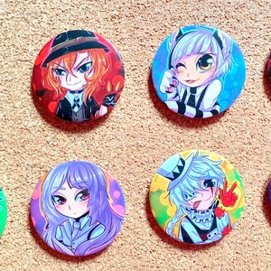Op de afbeelding: Een verzameling van acht ronde anime-personagebuttons. Elke button toont een andere karakterillustratie met levendige kleuren en gedetailleerde kunstwerken. De buttons zijn gerangschikt op een getextureerd, lichtbruin oppervlak.