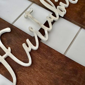 May include: A wooden sign with the word "Fur" in white raised letters. The sign is made of dark brown wood and has a rustic look.