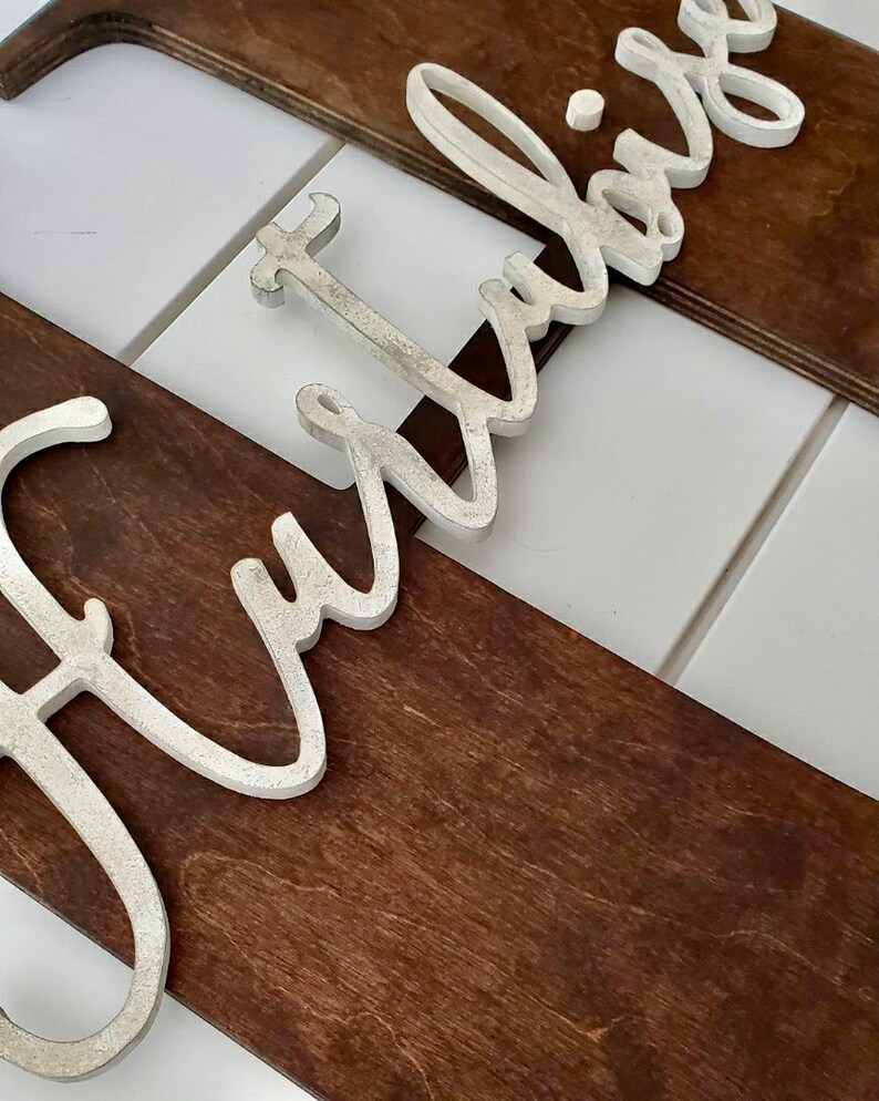 May include: A wooden sign with the word "Fur" in white raised letters. The sign is made of dark brown wood and has a rustic look.