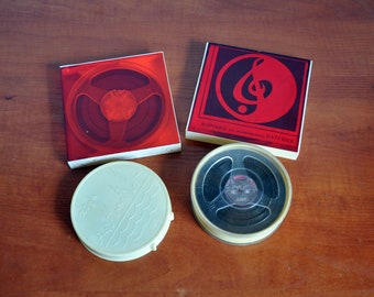 May include: Four vintage audio cassette tapes, two in their original red and white cardboard cases, one with a black and white label and a treble clef symbol, and one with a white plastic case with a wave design.