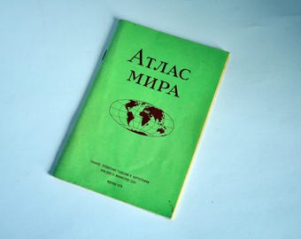 May include: Green book with the title "Atlas Mira" in brown lettering. The cover features a world map with a green background.