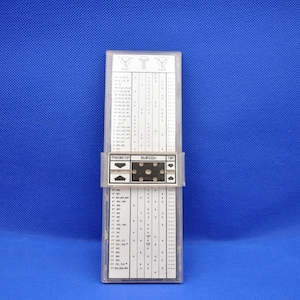 Könnte beinhalten: Ein Vintage-Elektronik-Komponentenidentifikator mit einem transparenten Kunststoffgehäuse. Das Gerät verfügt über eine weiße Karte mit schwarzem Text und Diagrammen, einschließlich der Wörter "ТРАНЗИСТОР ВЫВОДЫ ТИП". Der Hintergrund ist einfarbig blau.